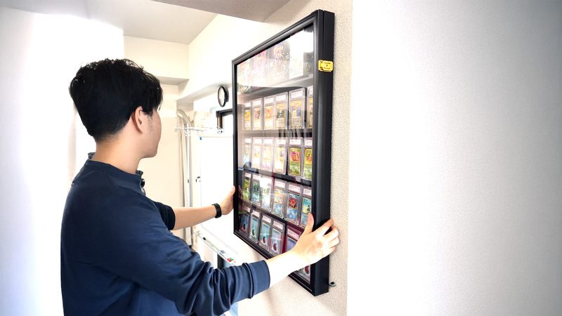 金具にディスプレイケースを引っかけて壁に取り付ける様子